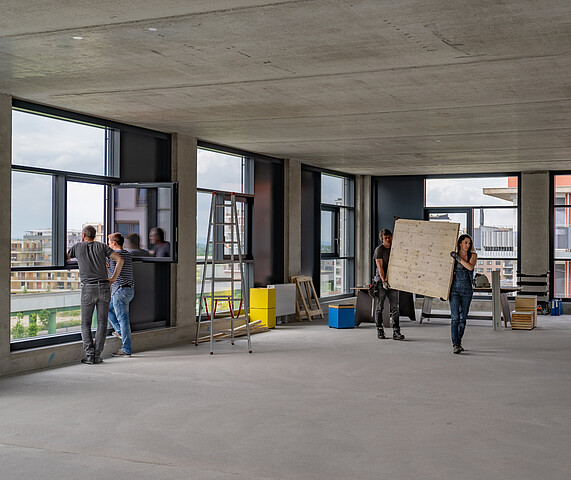 Eine Mietfläche des Gewerbehof Seestadt im Edelrohbau. Einige Handwerker sind bei der Arbeit zu sehen.