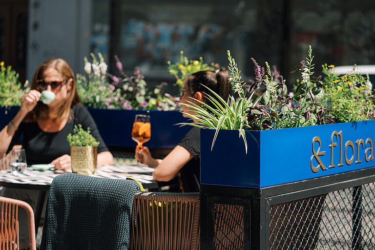 Gastgarten &flora Zwei Personen sitzen im Gastgarten mit Getränk