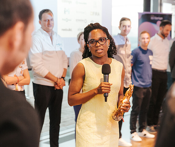 ViennaUP Startup Business Festival Vienna Woman in yellow dress speaking into a microphone to a group of people at a business event