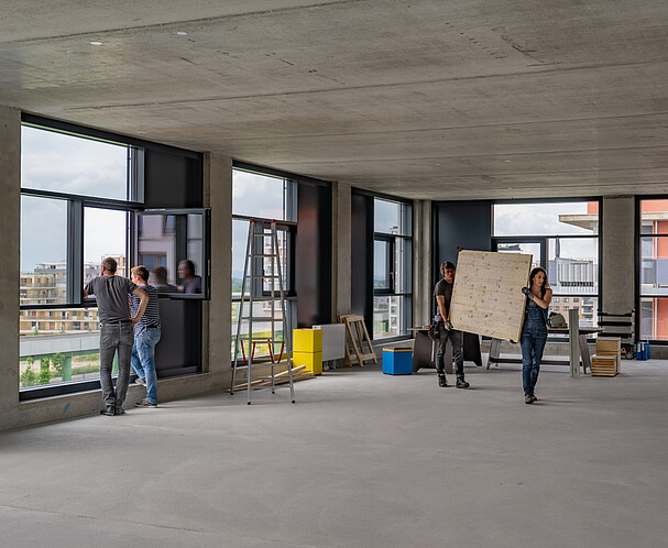 Eine Mietfläche des Gewerbehof Seestadt im Edelrohbau. Einige Handwerker sind bei der Arbeit zu sehen.