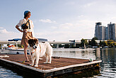 Woman with dog standing at pier and looking at tall buildings in Vienna