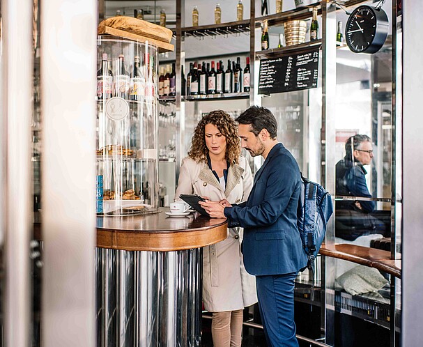 Leben-Arbeiten-Wien-Business Business in Vienna: Eine Frau und ein Mann stehen im Gespräch zusammen und schauen auf ein Tablet. Leben und Arbeiten in Wien.