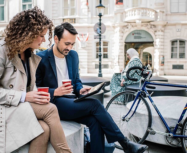 BusinessInVienna Ein Mann und eine Frau sitzen draußen und unterhalten sich.
