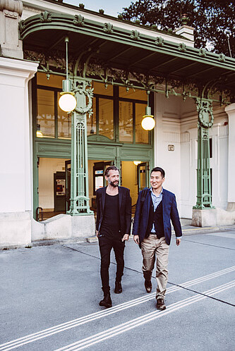 Leben-und-Arbeiten-Stadtpark-Ubahnhaltestelle Internationales Wien: Zwei Männer mittleren Alters entfernen sich von einer U-Bahnstation im Stadtpark Wien.