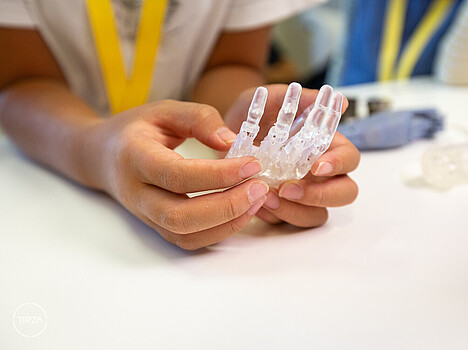 Technologie Workshops für Familien. Ein Mädchen mit Hut arbeitet mit einer Heißklebepistole