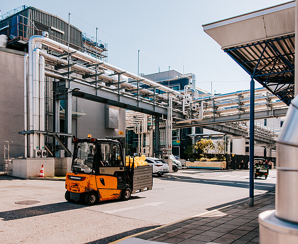 Orangener Gabelstapler fährt über ein Betriebsgelände